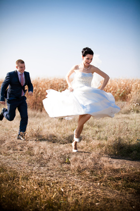 newly married couple chasing each other in field