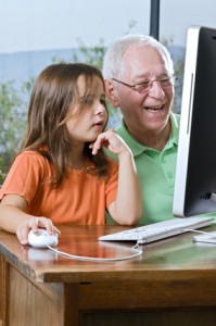 grandfather and granddaughter with computer at home