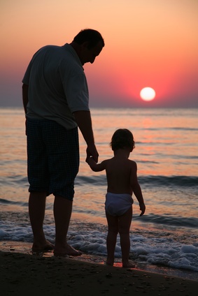 Grandfather with granddaughter on sunset at sea