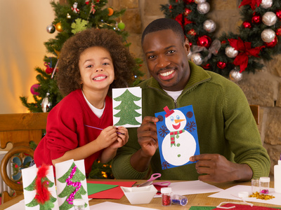 African American father and mixed race son making Christmas cards