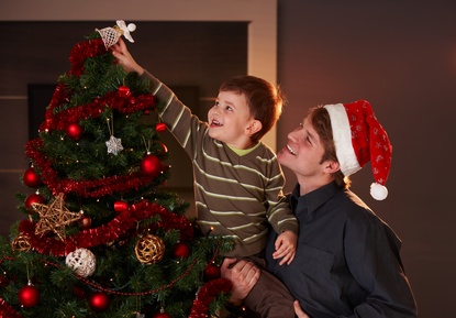 Dad helping boy to decorate christmas tree