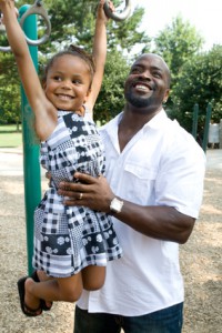 A father helps his daughter on the playground