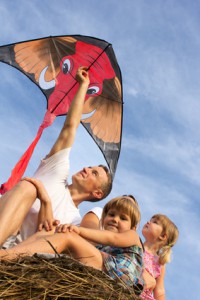 The family outdoors flying kite in the sky