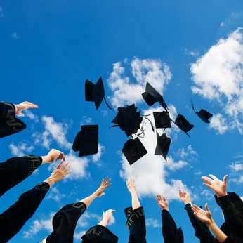 high school graduates tossing up hats over blue sky.